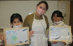 古賀先生と作品を持った2人の女の子の画像