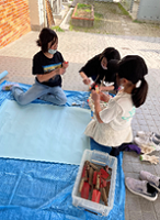 広げた模造紙の前の小学生たちの写真