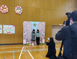 桜並み木の写真の映えスポットで写真を撮る卒業生の画像1