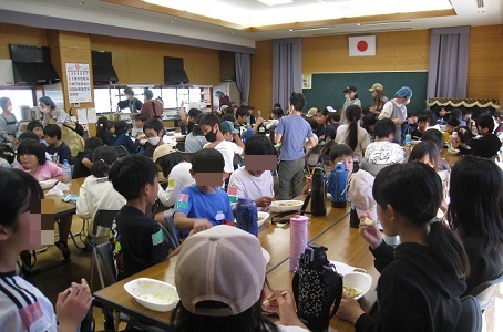 公民館で6年生調理のカレーをみんなで会食しているようす