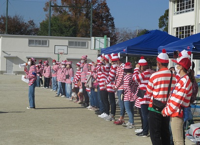 一列に並んだWさん役の有志の前で、子ども達に挨拶する子育連会長の写真