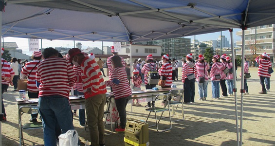 イベントを支えるテント下の本部にも、赤白ボーダーシャツ姿のWさん役スタッフが大勢いる写真