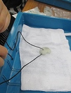完成した白い勾玉に、黒いひもを通しているようす。これで完成。