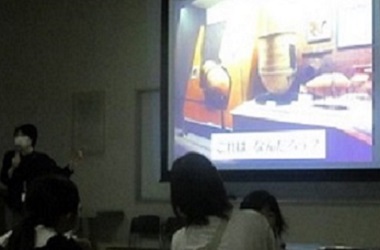 暗くなった会場の正面に映し出される古代の甕棺など、博物館収蔵品説明の画像