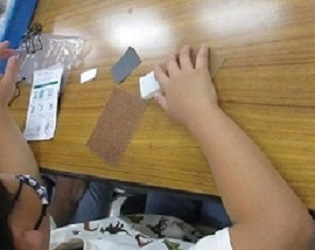 紙やすりで石を削り始めた子どもの手元写真