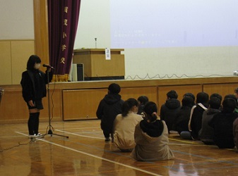 前でスタンドマイクを使って全体の司会進行を行う計画委員会の高学年児童