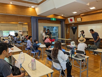 公民館講堂に着座する６組の親子連れの前に立つ、青育連会長と講師