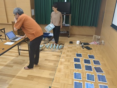 開始前、二人の講師が15対のタブレットとロボットを並べてセットしている様子