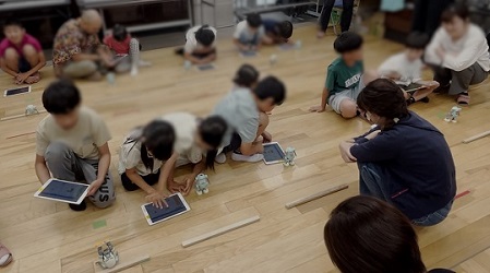 後方の床の上にセットされた障害物を超えてゴールまで走らせるプログラムに挑戦中の子ども達