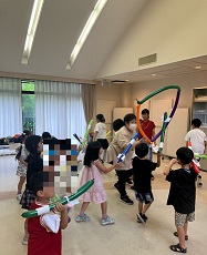 講師が3本の風船で作った三角の輪に、風船ロケットを通そうと追いかけている子ども達