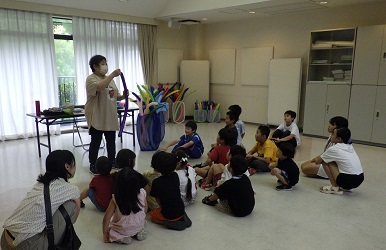 バルーンの作り方の説明に、座って耳を傾けている子ども達