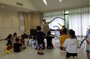 長い風船バルーンを、指でつまんだり、引っ張って捻ったりして犬や剣を作ろうとしている子ども達