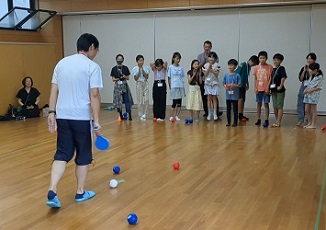 白い球からの距離を講師が計測に集中する参加者。結果発表に、飛び上がって喜ぶ子もいる様子。