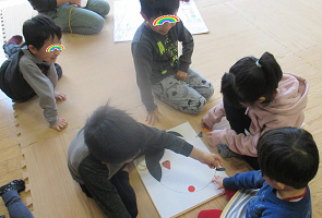 お多福の福笑いを楽しんで見ている子ども達