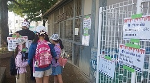 飼育小屋前で校歌を歌って答を確かめる子ども達の写真