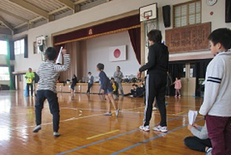 子どもたちが紙ヒコーキを飛ばし飛距離を競争している様子