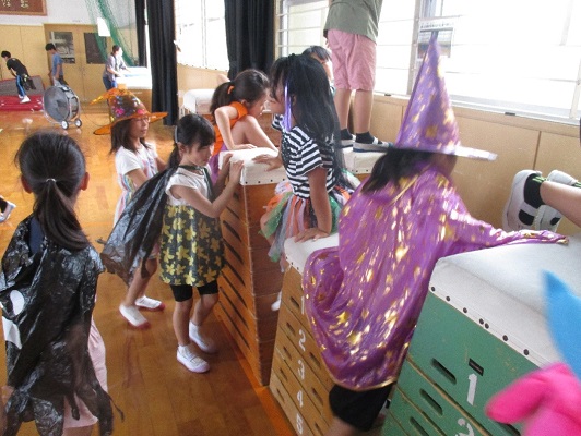 お菓子探しゲームでとび箱の周りのお菓子を子ども達が探している様子