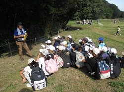 子どもたちが遊びの達人からカモフラージュというゲームのルール説明を聞いている様子