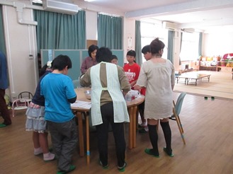 テーブルの周りに集まる大人と子どもたちの様子