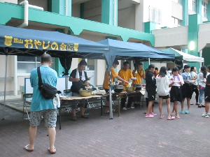 おやじの会がカレーやデザートを子どもたちに食べさせている様子