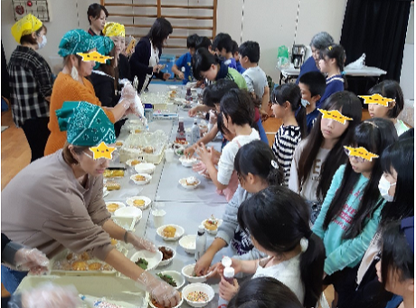 大人が子どもたちにカップケーキ作りを指導