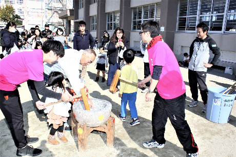 子どもたちが大人と一緒に餅をつく様子