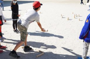 下手でモルックを投げて12本のスキットルを倒します