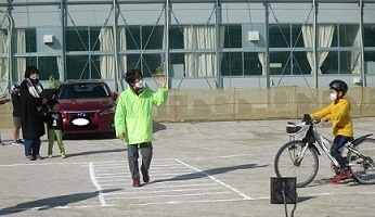 停止線で止まって、歩行者の横断を待っている自転車に乗った子どもの写真