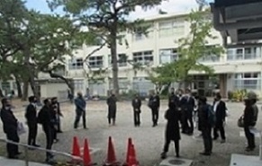 密を避けて円陣を組み，屋外で反省会をする大人スタッフの皆さん。