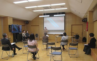 前方プロジェクター画面と生ギター弾き語りの準備がされた会場