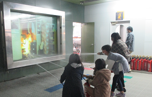 室内で発生した火災（映像）を、水を代わりに詰めた消火器で消し止めます。