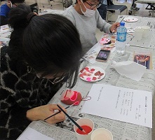 お面に赤い絵具を塗る子どもの写真