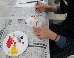 自分が選んだお面に絵具を塗る子どもの写真