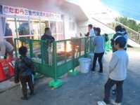 フェンスの外側からおき火を眺めるこどもたち