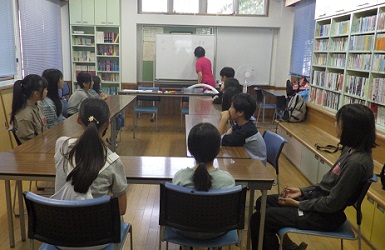 公民館でコの字型に座って講師の話を聴く子ども達