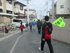 「横断中」の旗を手に子ども達に寄り添って歩くレンジャーさんの写真
