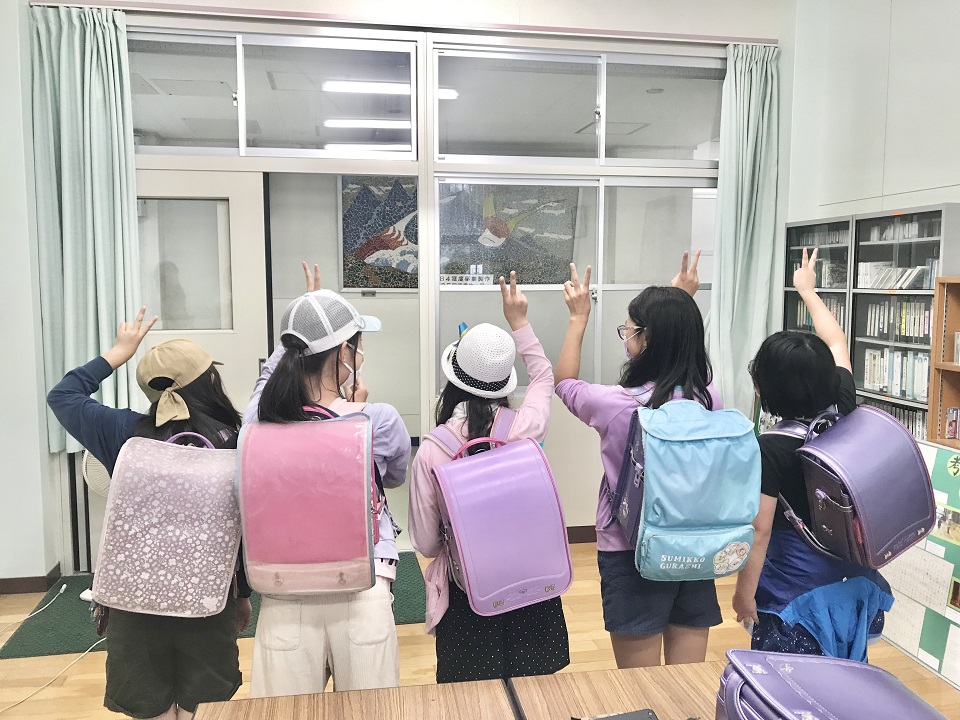 小学生がランドセルをかるって背中向けにピースをする写真