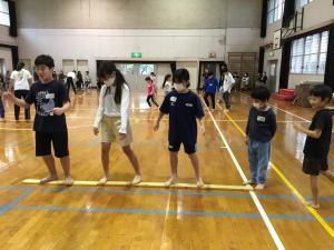 床に置いたロッド（細い板）に乗ってトレーニングする子どもたち