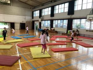 床に置かれたマットに飛び移りながら鬼ごっごをする子どもたち