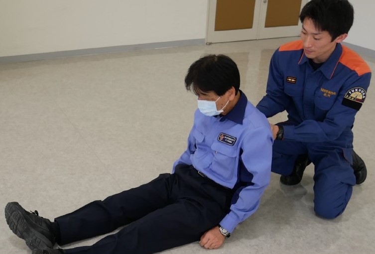 １　仰向けに寝ている傷病者の上体を起こして，背中側から支える。