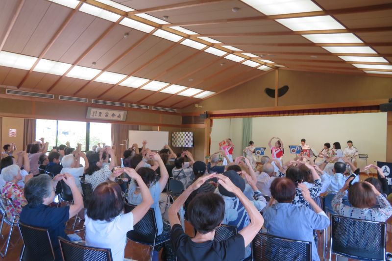 お客様と一緒に曲の振り付けを踊る福岡市消防カラーガード隊の写真