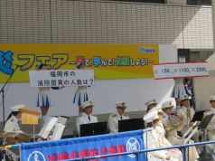 演奏に合わせてクイズを出題する福岡市カラーガード隊の写真