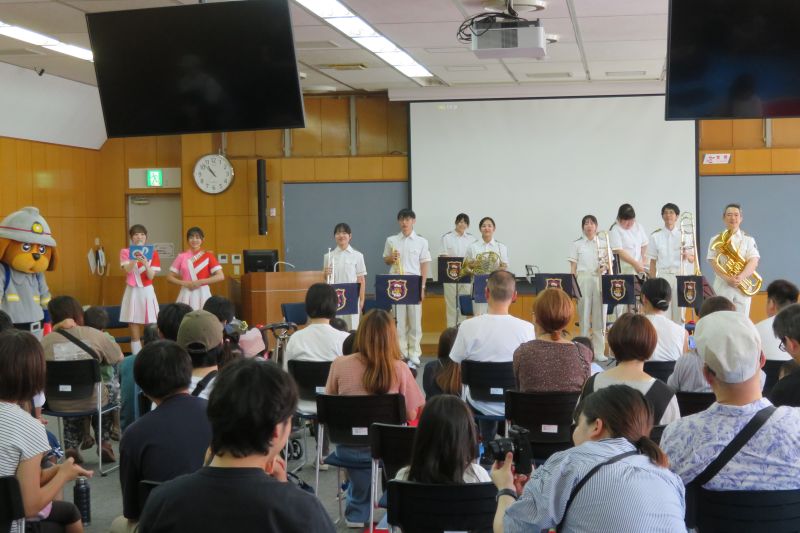 福岡市消防音楽隊の隊員8名とカラーガード隊2名とファイ太くんの写真