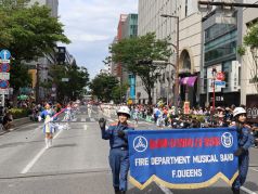 活動服を着用し、音楽隊の横断幕を持ってパレードをする隊員の写真