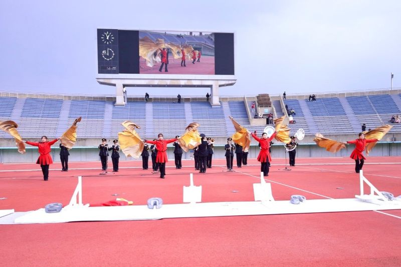 陸上競技場内で演奏と演技を行う福岡市消防音楽隊の写真