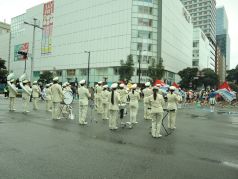 天神交差点で演奏と演技を行う福岡市消防音楽隊を背面から撮影した写真