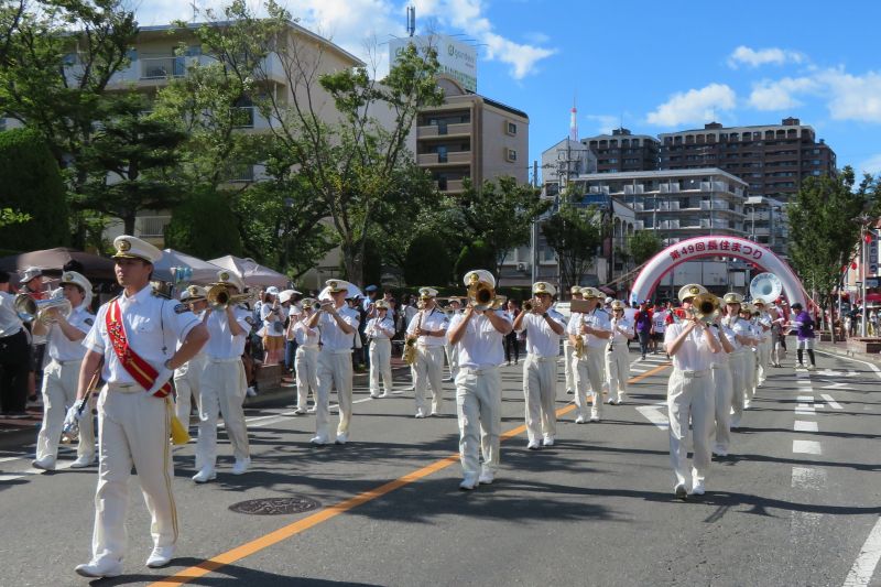 消防音楽隊を率いるドラムメジャーと、パレード演奏を行う消防音楽隊の写真
