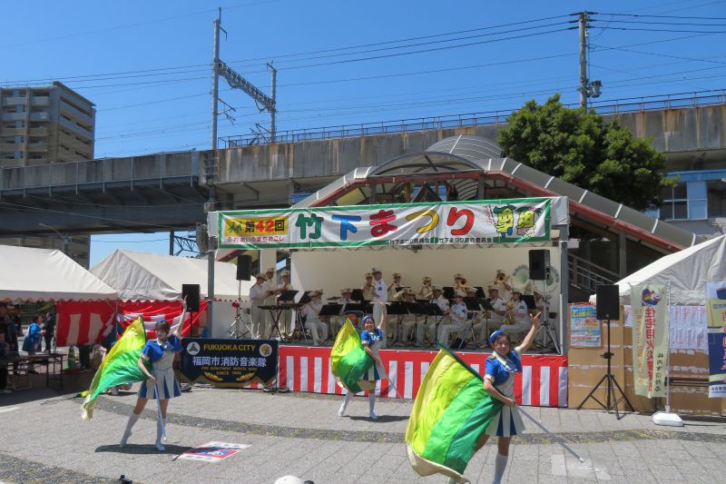 jr竹下駅前で演奏演技をする福岡市消防音楽隊カラーガード隊の写真