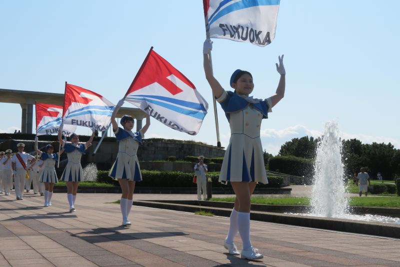 パレードでフラッグを演技を行うカラーガード隊の写真