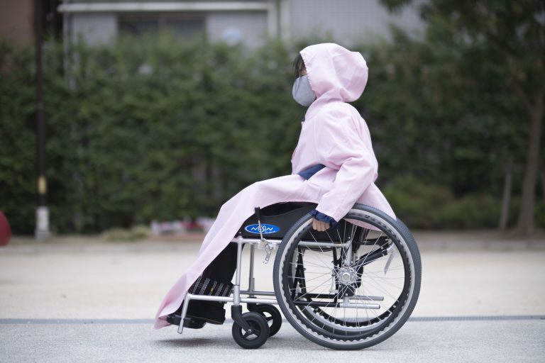 レインコートを着て車いすに乗っている女性の写真